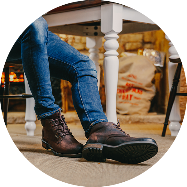 Man sat on a chair wearing a pair of brown Cotswold Birdwood Work Boots 