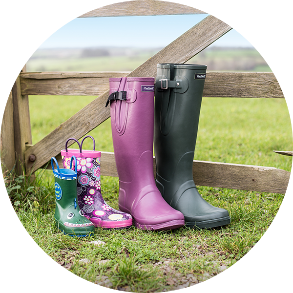 Cotswold wellingtons for a boy, girl, woman and man in front of a gate in the countryside