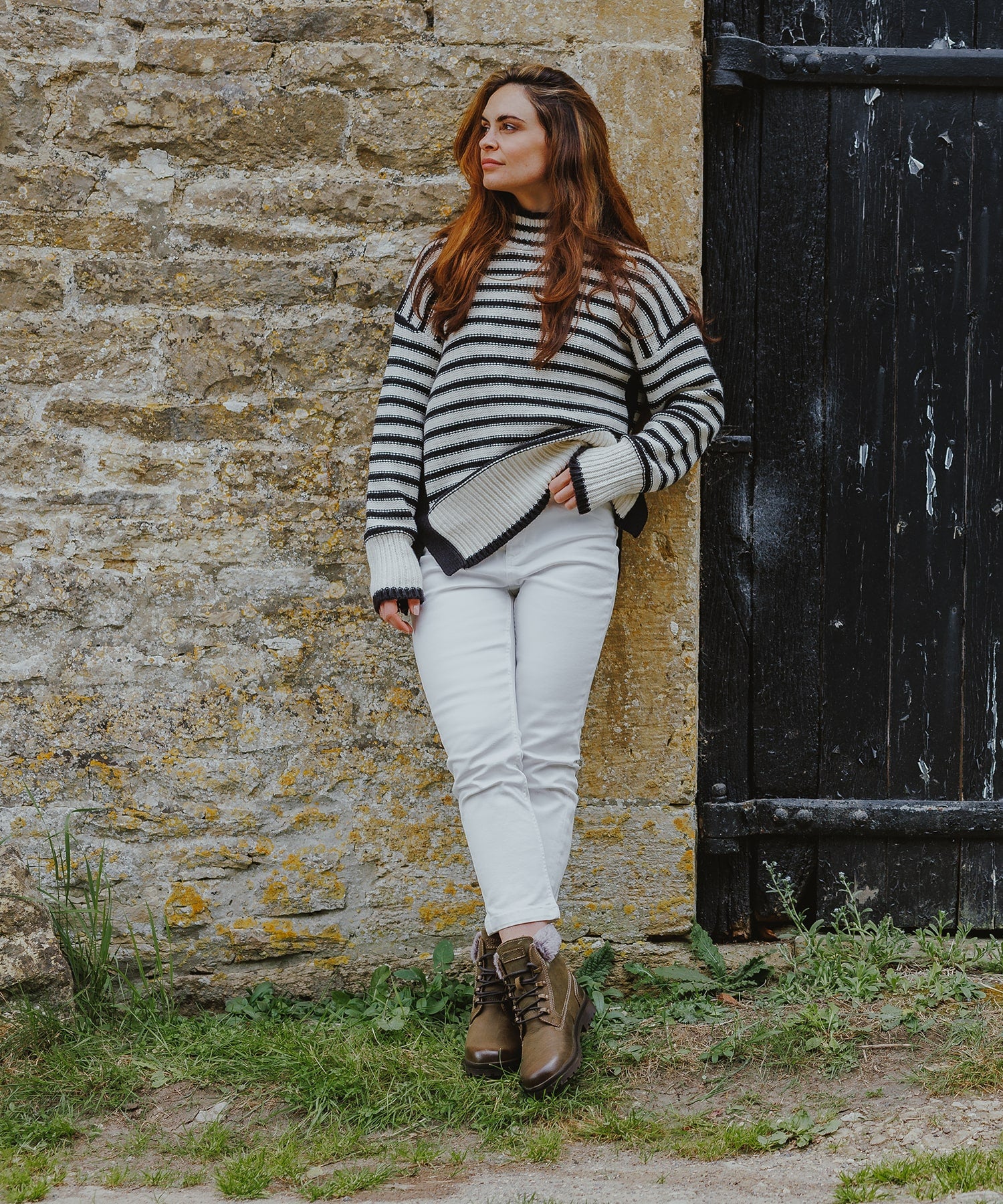 Woman leaning against a wall, wearing a pair of Cotswold boots